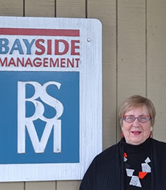 Photo of Barbara Boyd in front of Bayside Management sign.