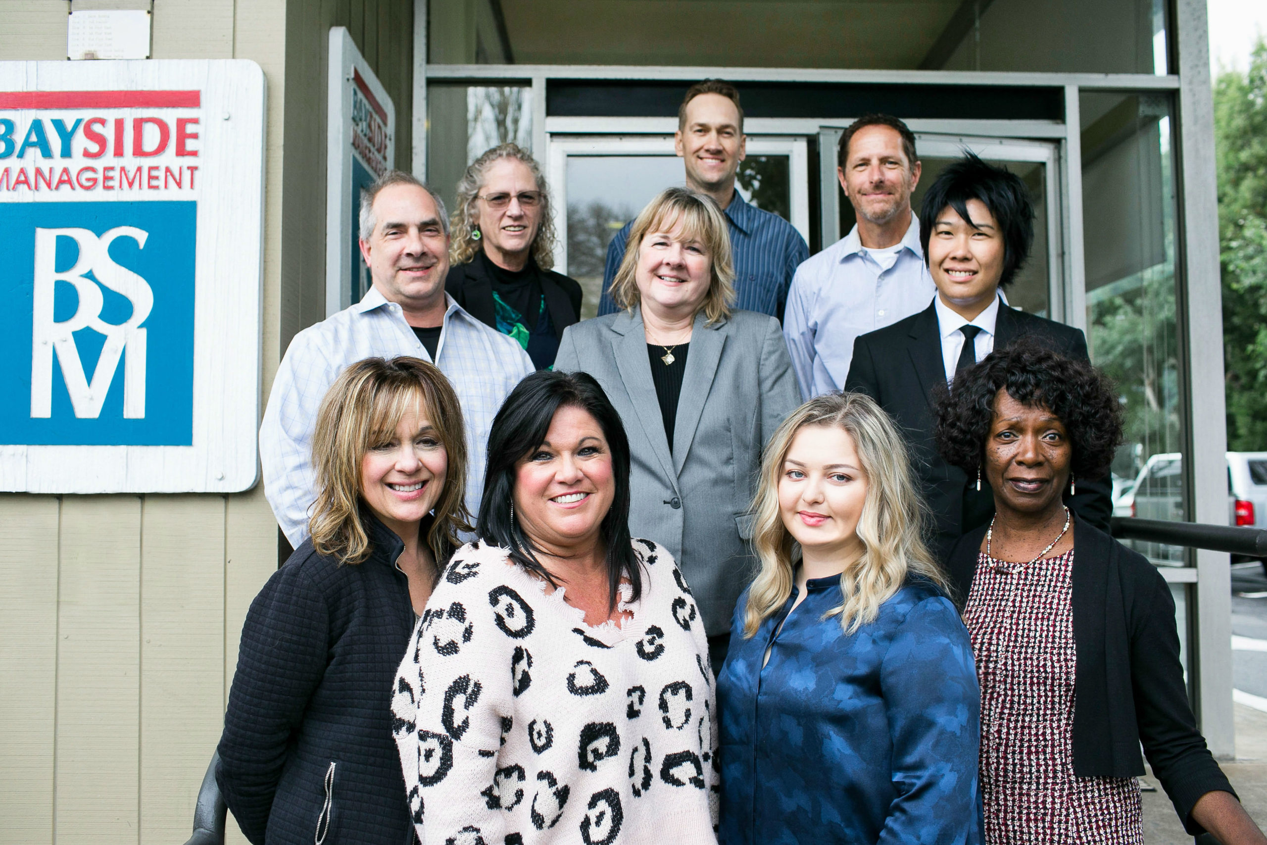 The Bayside Management team on the office front steps in front of the Bayside Management sign. Use Bayside Management for property management in San Mateo County.