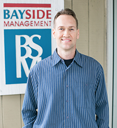 Photo of Dylan Motchar in front of Bayside Management sign